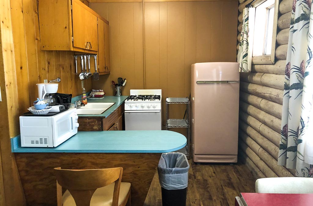 A clean Kitchen at Island Acres Resort Motel. There is a microwave, a sink, a full size stove and oven, and a full size vintage refrigerator.