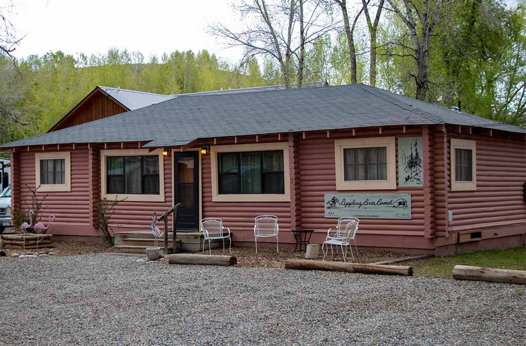 Rippling River Ranch Cabin Island Acres Resort Motel is a log cabin with guest seating in front
