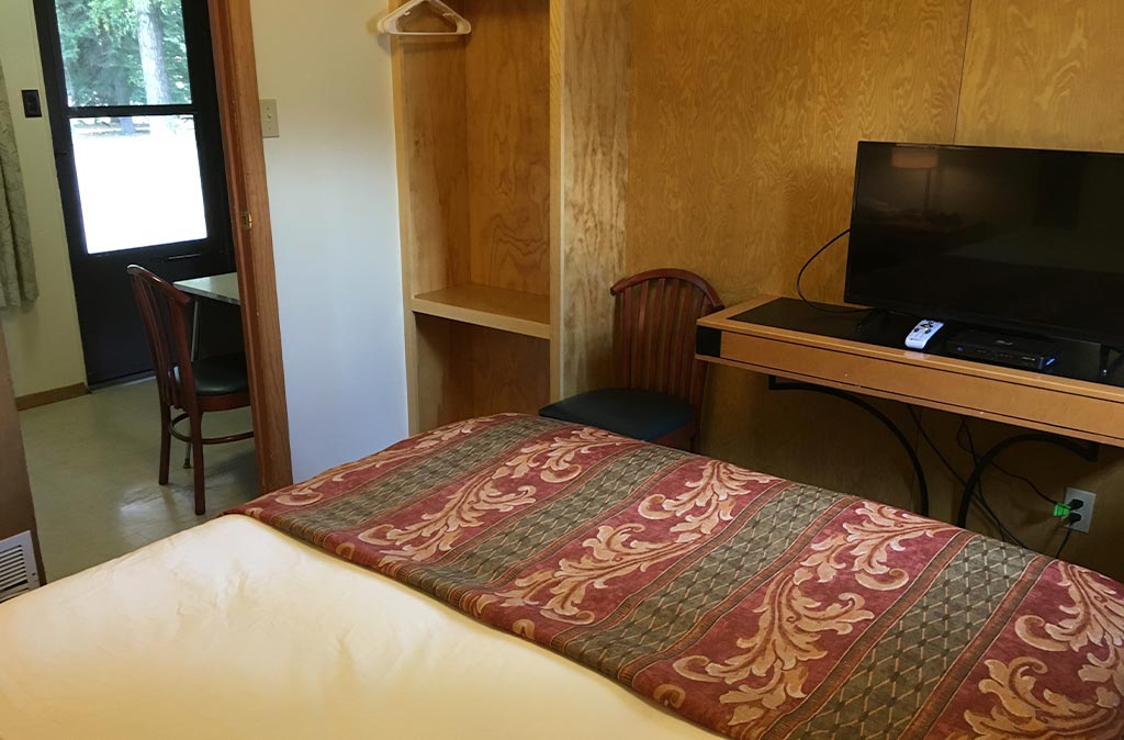 Photo of two-bedroom kitchenette unit at Island Acres Resort Motel showing queen bed and flat screen TV.