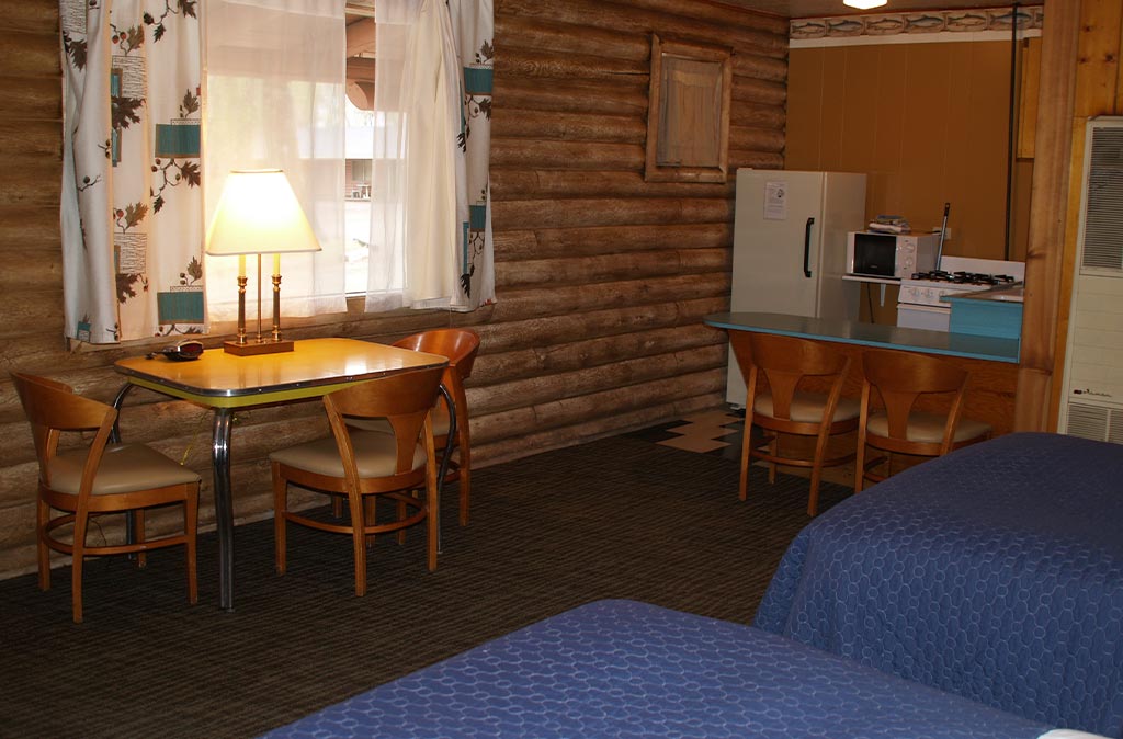 Photo of Queen Studio Unit at Island Acres Resort Motel showing two queen beds, mid-century dining table, and kitchen area.
