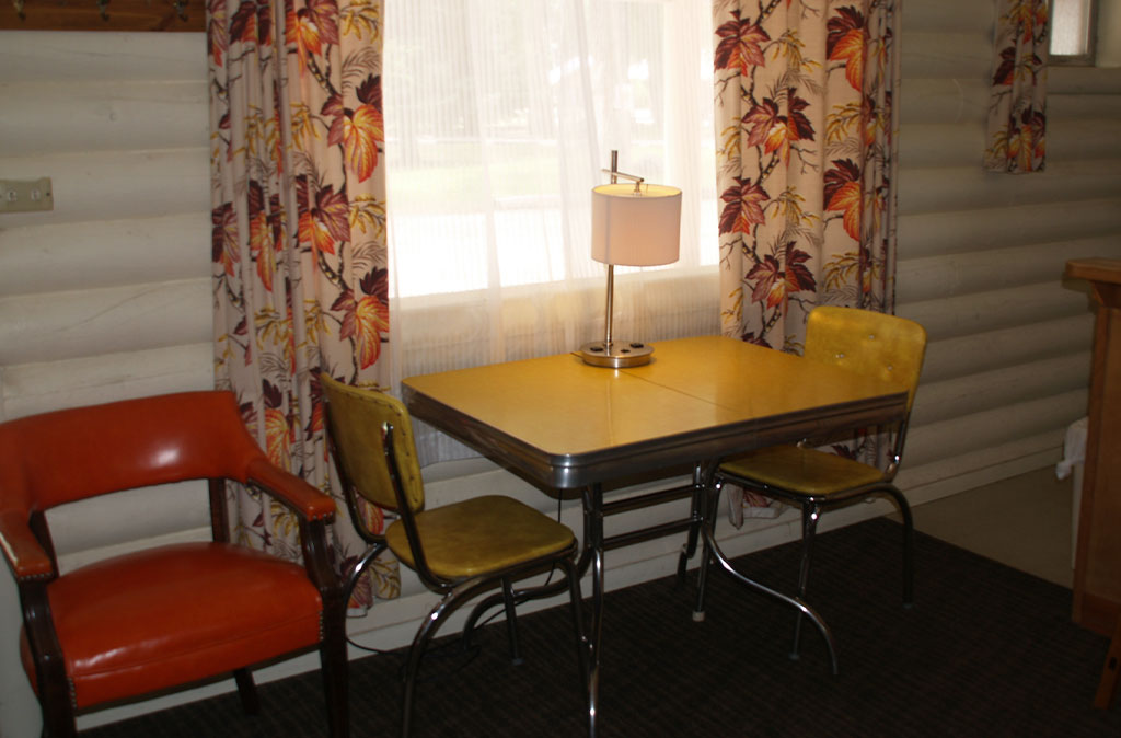 Photo of vintage table at Island Acres Resort Motel against a white painted loclog wall.
