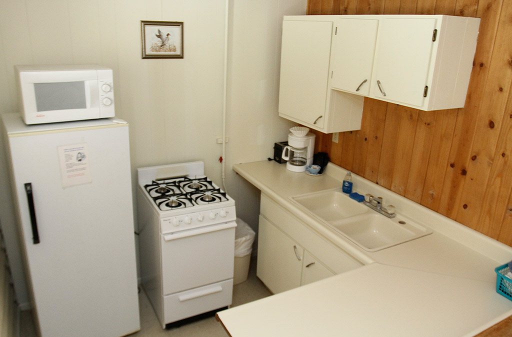 Photo of kitchen in unit 12 at Island Acres Resort Otel showing fridge, microwave, small stove and oven, sink, counter space, and cabinets.