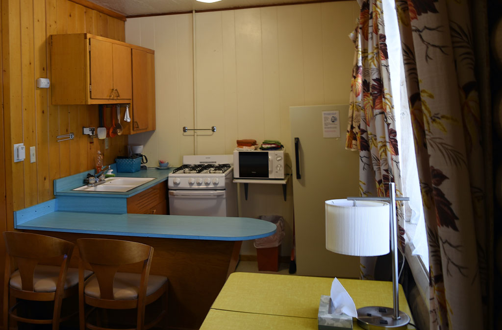 Photo of kitchen in unit 14 at Island Acres Resort Motel showing fridge, microwave, stove and oven, skink, countertops, and cabinet space.