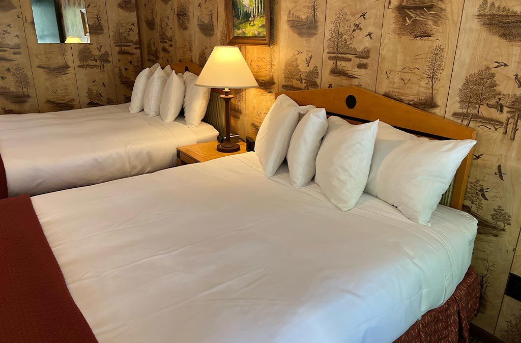 Photo of Deluxe Studio Unit at Island Acres Resort Motel showing two queen beds against a vintage panel wall.