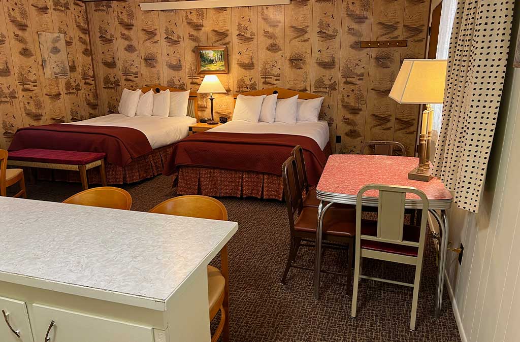 Photo of Deluxe Studio Unit at Island Acres Resort Motel showing two queen beds, kitchen seating, and dining area.