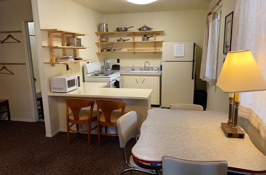 Photo of Deluxe Studio Unit at Island Acres Resort Motel showing dining area and kitchen with newly renovated mid-century open shelving.