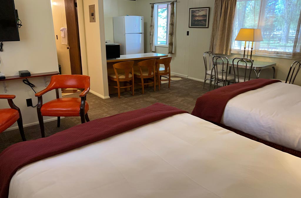Photo of Deluxe Studio Unit at Island Acres Resort Motel showing two queen beds, seating area, kitchen, and dining area.