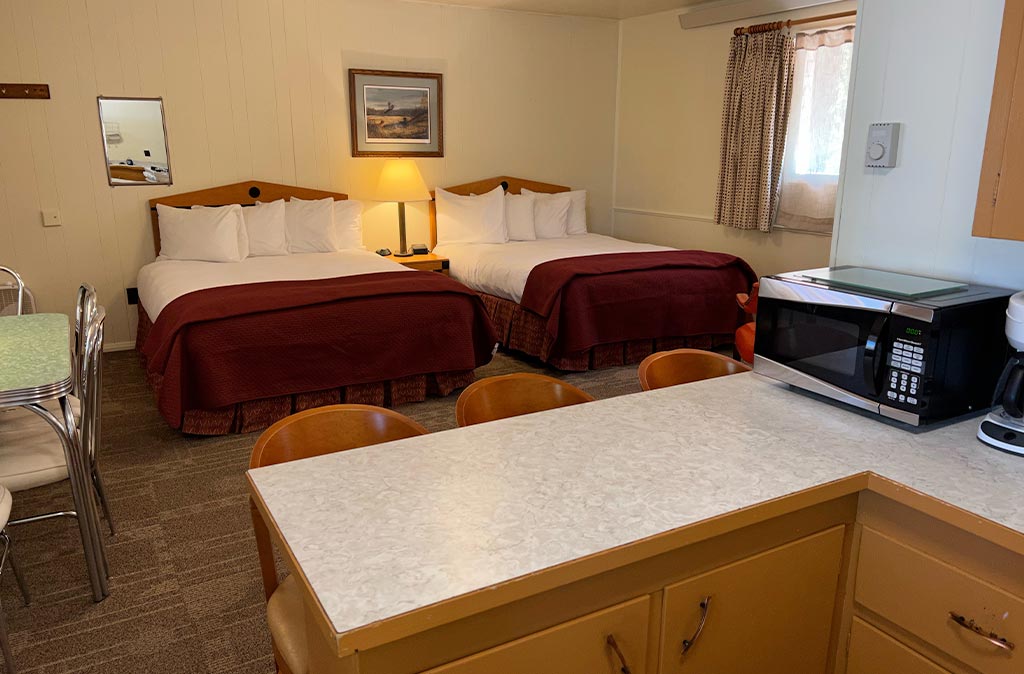 Photo of Deluxe Studio Unit at Island Acres Resort Motel showing two queen beds and dining area from view of the kitchen.